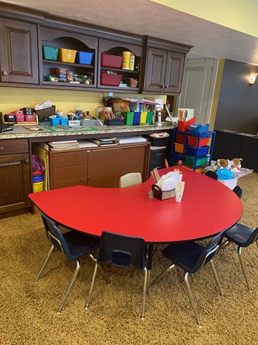 Red craft table with art supplies and storage bins