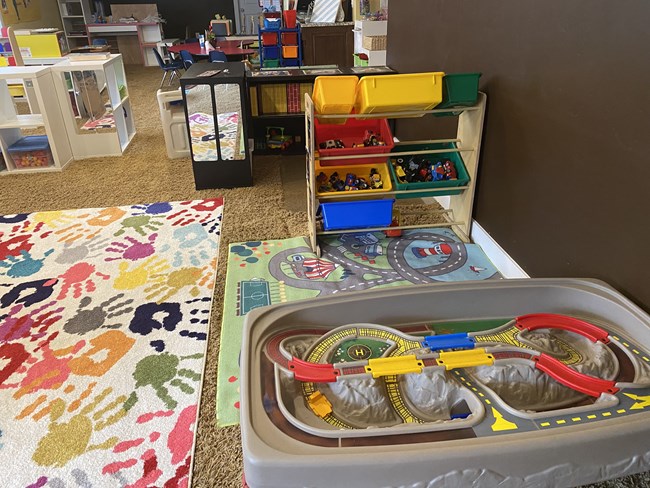 Train track table and building toys on a colorful handprint rug